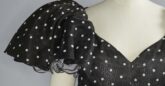 A mannequin wearing a black and white polka dot dress by Hardy Amies with full puff sleeves