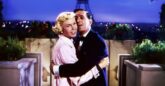 A man and a woman embrace against a backdrop of the Eiffel Tower at night