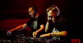 Two males DJing next to each other.