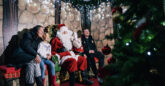 A smiling family meeting Father Christmas at Adventure Island’s Wonderland, with children receiving festive gifts in a cozy, decorated elf cottage.