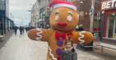 A child stands in front of a person dressed in a gingerbread man costume on Southend High Street.
